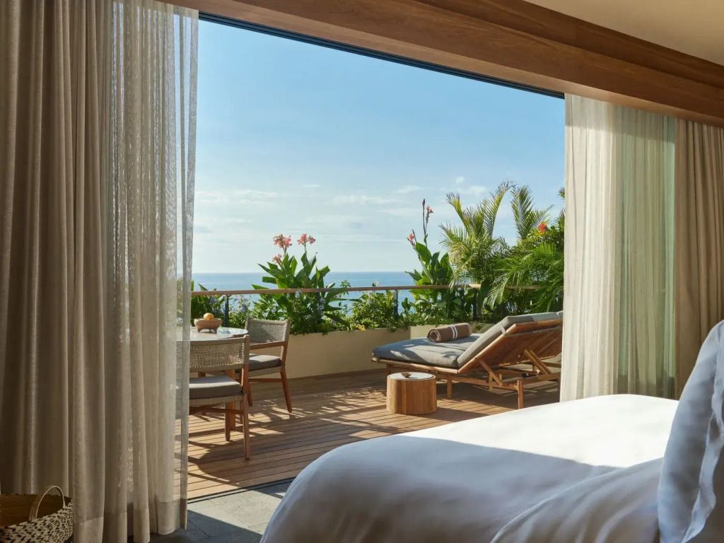 Terrasse mit Meerblick und gemütlicher Sitzgelegenheit vor einem Schlafzimmer.