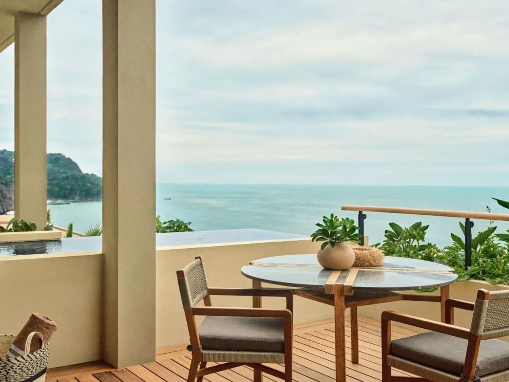 Holzterrasse mit stilvoller Sitzgruppe und Blick auf das Meer.