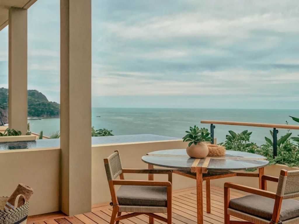 Terrasse mit Tisch, Stühlen und Blick auf das Meer.