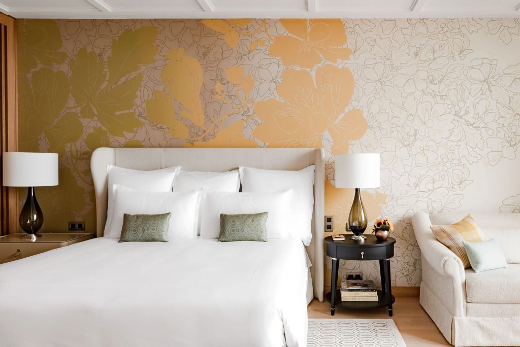 Luxuriöses Schlafzimmer mit kunstvollem Tapetendesign und hochwertiger Bettwäsche.