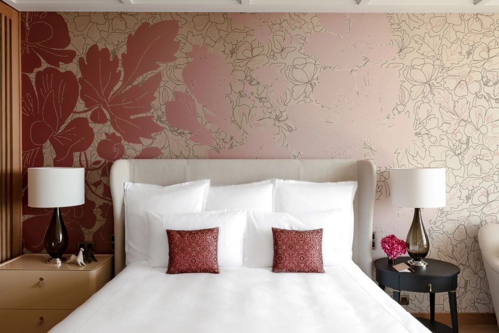 Gemütliches Schlafzimmer mit kunstvoller Tapete und eleganten Kissen auf einem großen Bett.