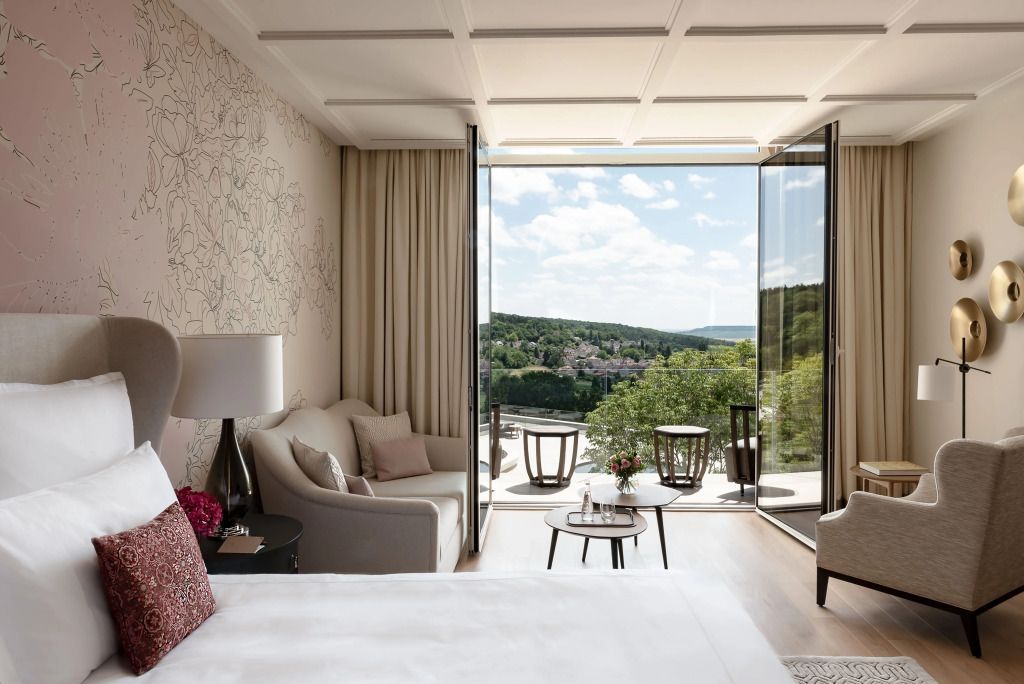 Panoramablick aus einem Zimmer auf die grüne Landschaft mit komfortablen Sitzgelegenheiten.
