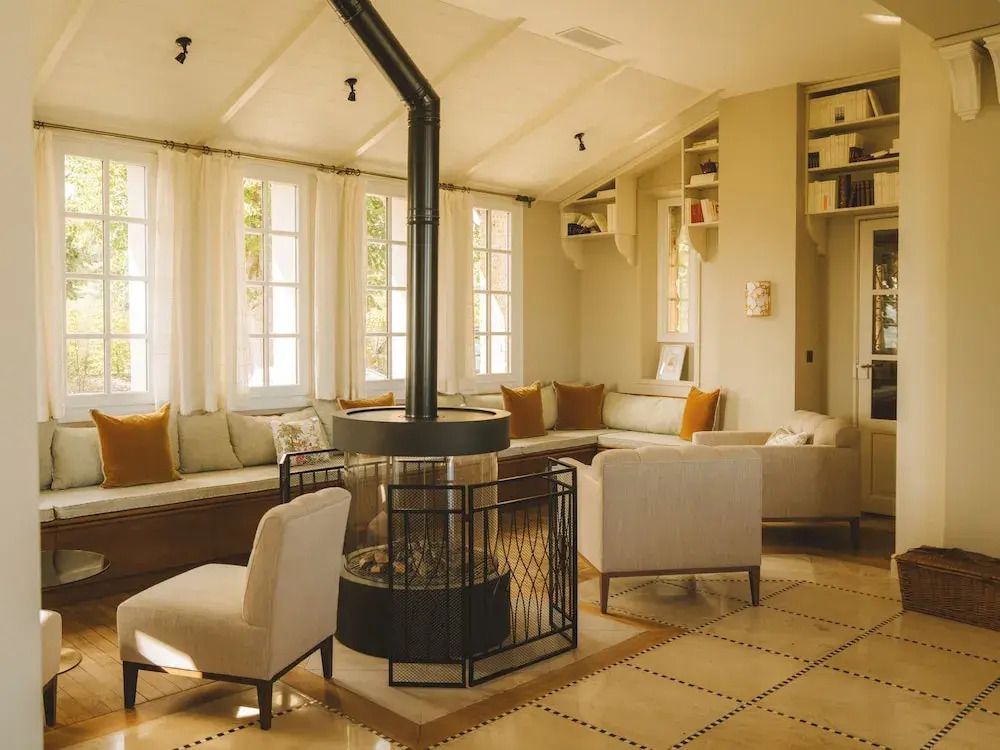 Gemütlicher Loungebereich mit Kamin und großen Fenstern, helle Sofas und Sessel.