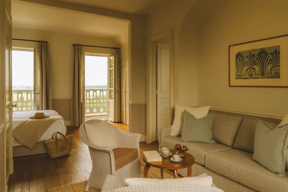 Gemütlicher Wohnbereich mit Sofa, Sesseln, Tee und Balkonzugang, warmes Ambiente.