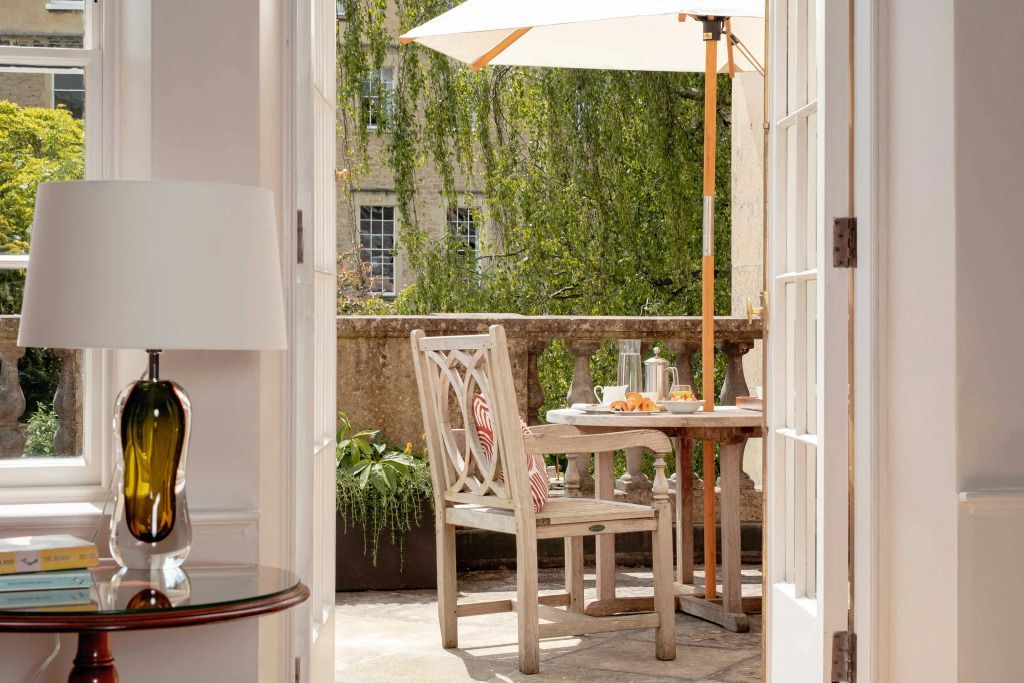 Balkon mit Tisch und Stühlen sowie Sonnenschirm und grüner Aussicht