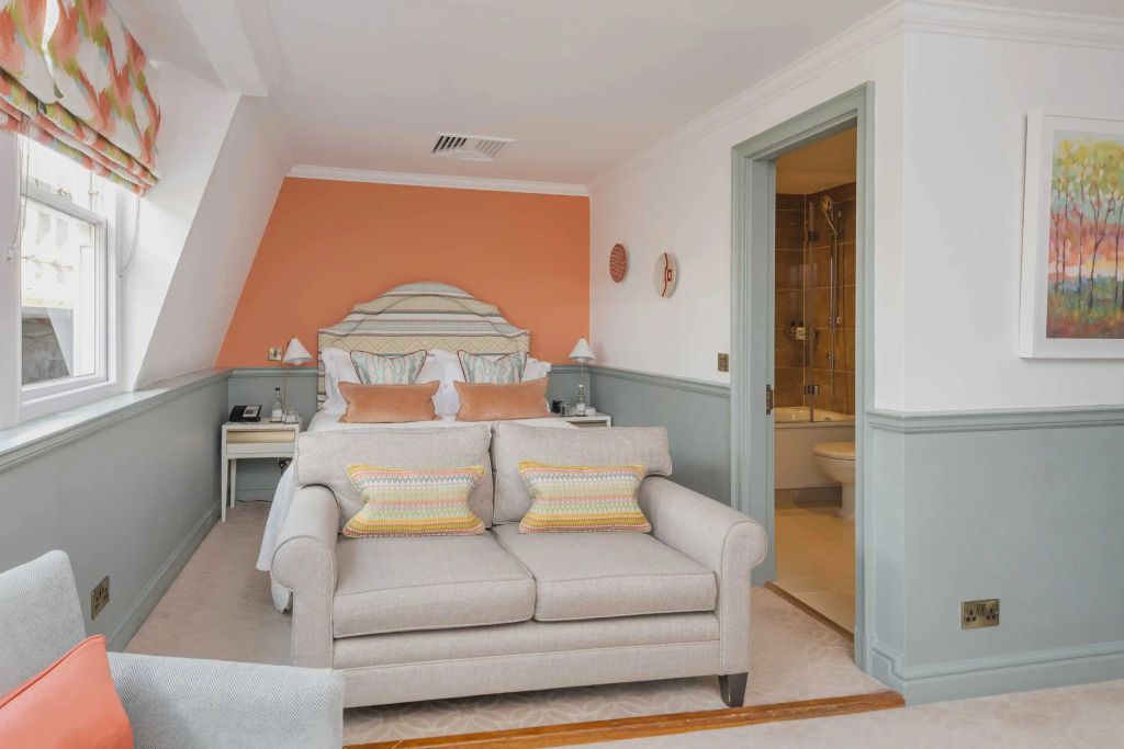 Helles klassisches Zimmer mit beigem Sofa und orangefarbenen Akzenten.