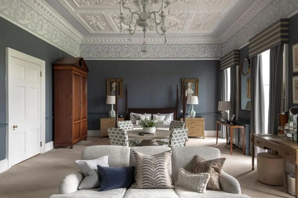 Luxuriöses Schlafzimmer mit kunstvollem Deckenrelief und gemütlichem Sofa