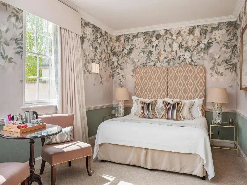 Elegantes Schlafzimmer mit Doppelbett, floralem Wanddekor und natürlichem Licht