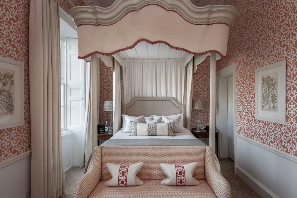 Himmelbett in geschmackvoll gestalteter Suite mit klassischen Tapeten und eleganten Kissen