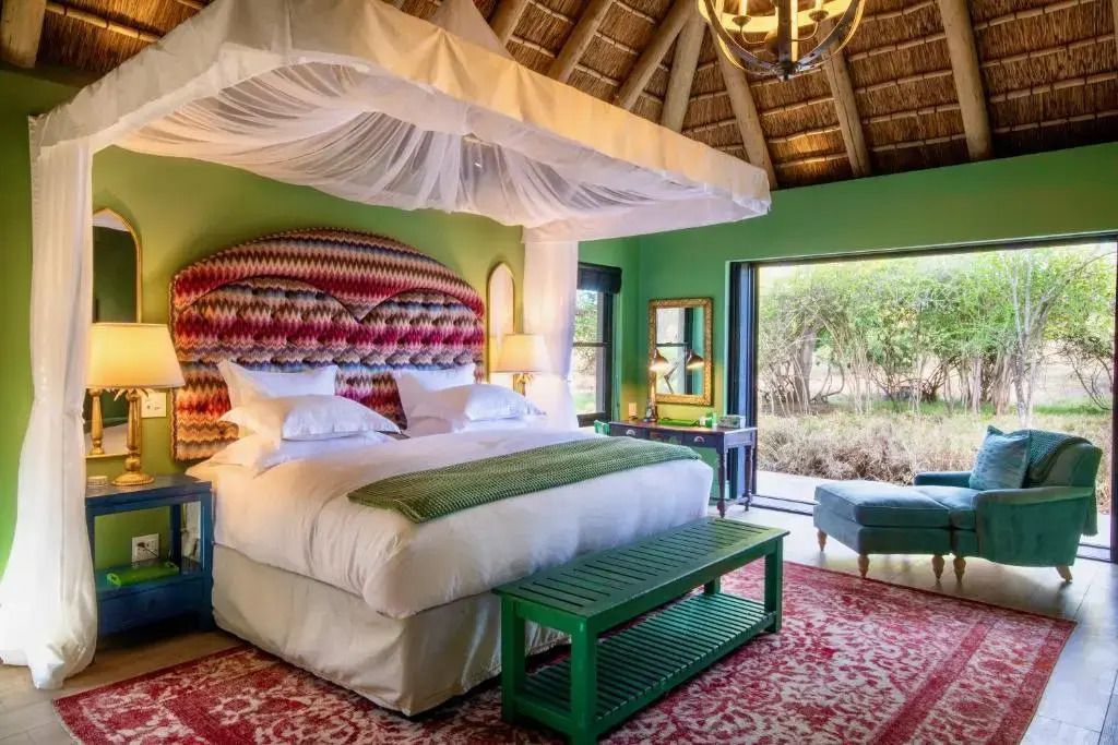 Elegante Suite in warmen Farben mit Himmelbett, grünen Wänden und Blick auf die Natur