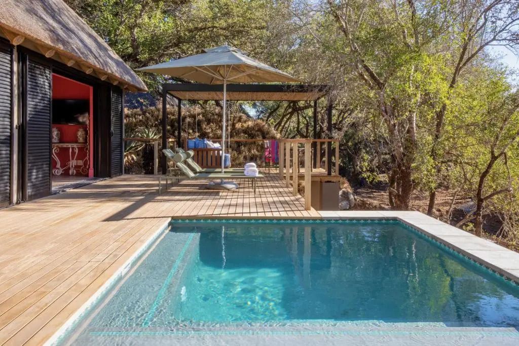 Privater Pool auf Holzterrasse mit Liegestühlen, umgeben von Natur
