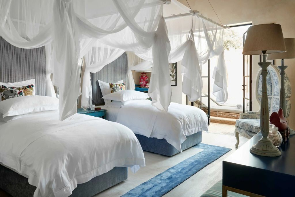 Schlafzimmer mit zwei Himmelbetten und weißem Dekor