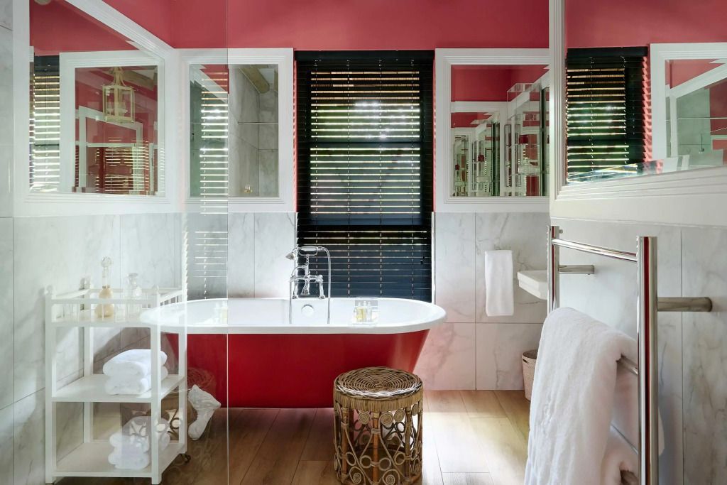 Badezimmer mit freistehender Badewanne in lebendigem Rot und großen Spiegeln