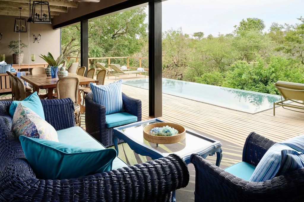 Terrassenbereich der Suite mit Lounge-Möbeln und Blick auf den Infinity-Pool