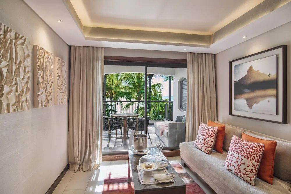 Wohnzimmer der Grand Suite mit Zugang zur Terrasse und Blick auf Palmen und Meer