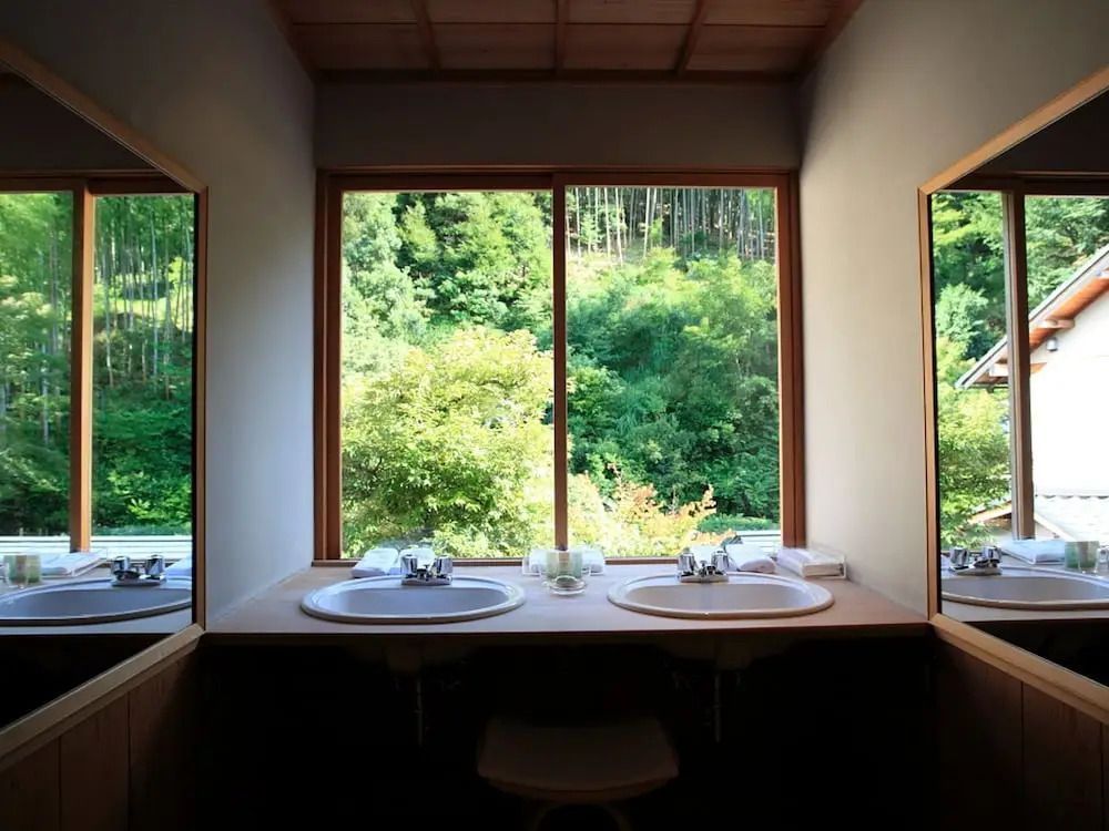 Waschbereich mit zwei Waschbecken und großem Fenster zum Garten