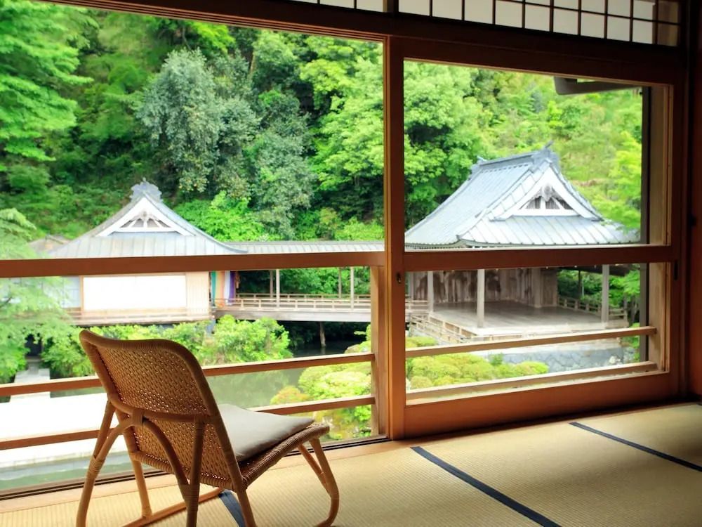 Blick aus Zimmer auf grüne Landschaft und traditionelle Gebäude