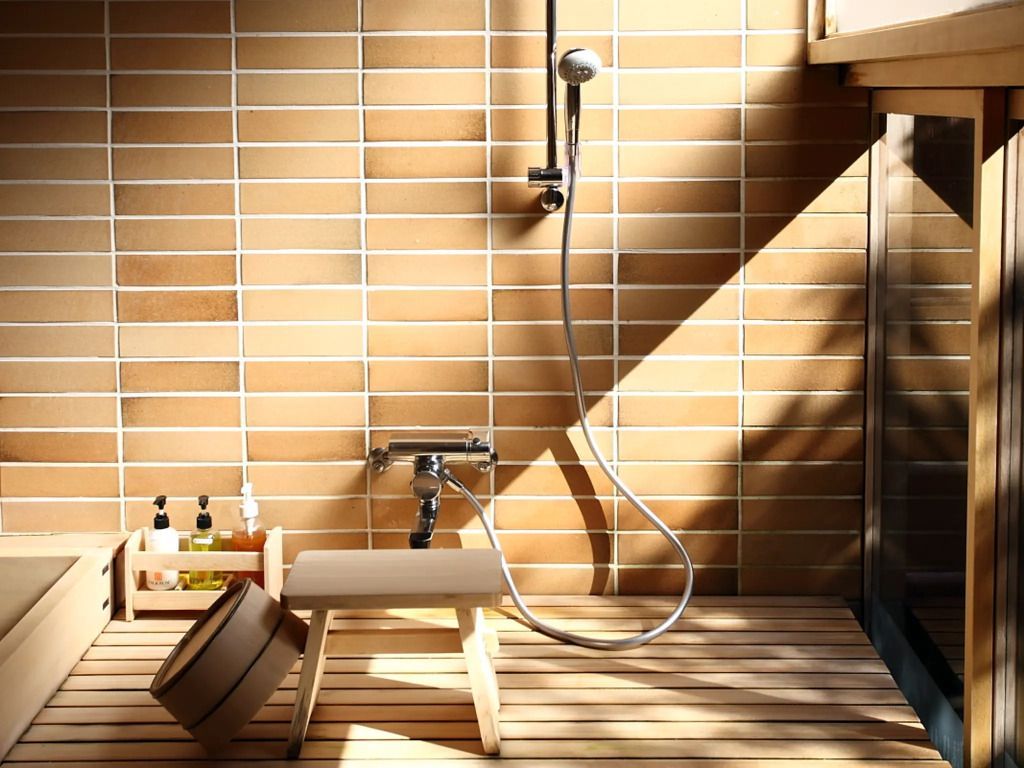 Japanisch inspiriertes Badezimmer mit Holz- und Kachelelementen. Tageslicht fällt schräg ein.