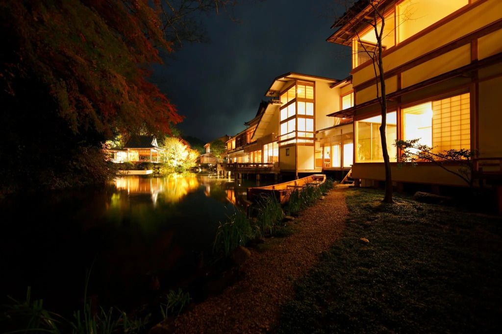Hotelarchitektur am Wasser bei Nacht mit beleuchteten Fenstern und reflektierendem See.
