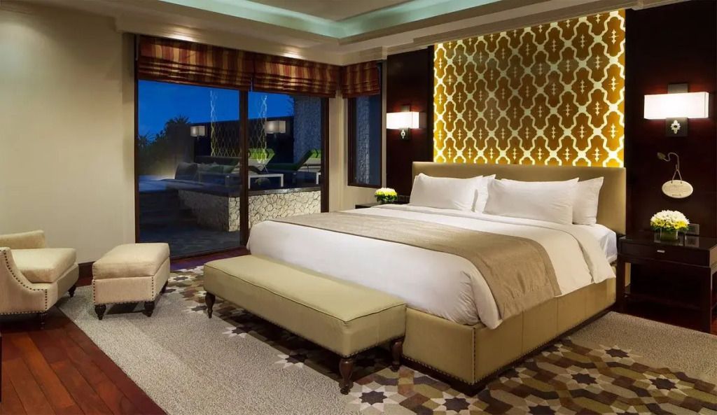 Luxuriöses Schlafzimmer mit Doppelbett und Poolblick in einer Villa bei Nacht