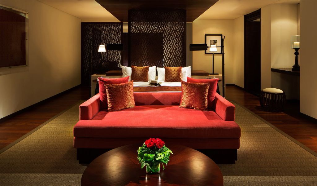 Elegantes Schlafzimmer mit rotem Sofa und luxuriösem Doppelbett