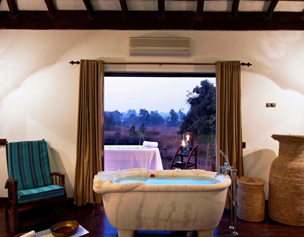 Badezimmer mit freistehender Wanne und Aussicht auf die Natur durch große Fensterfront