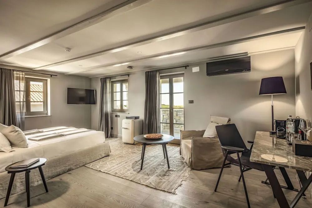 Geräumiges Zimmer mit Sitzbereich, Flachbild-TV und großen Fenstern.