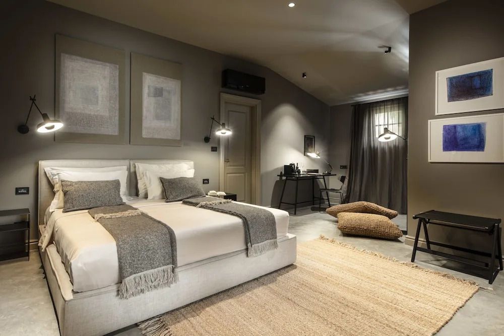 Elegantes Schlafzimmer mit Doppelbett, Schreibtisch und stilvoller Beleuchtung.