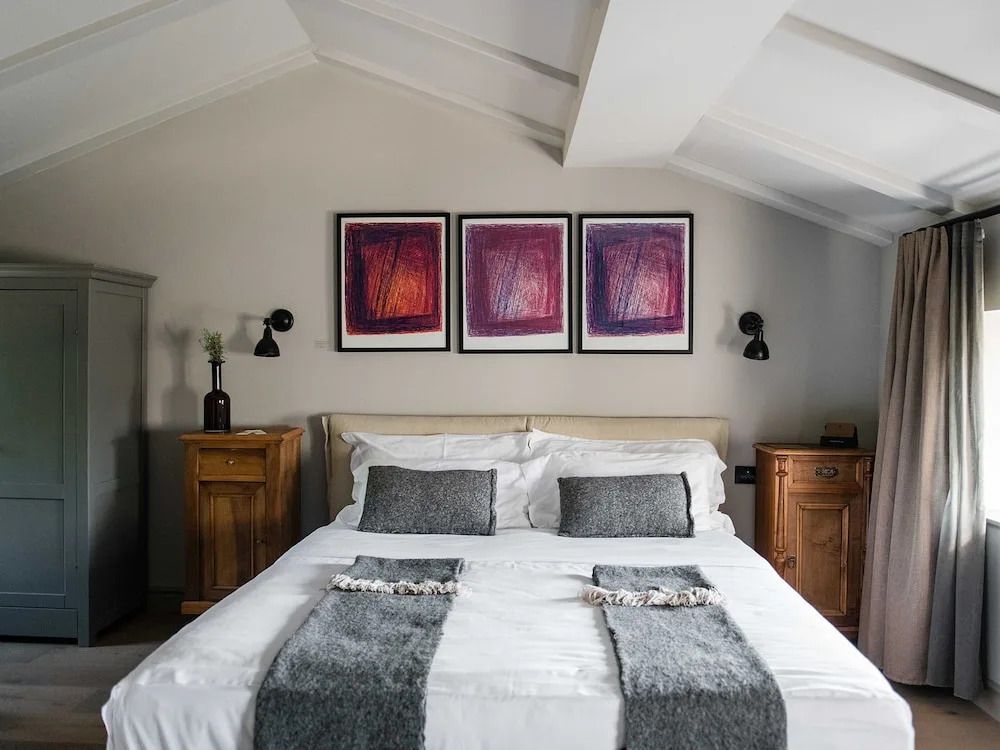 Helles Schlafzimmer mit Doppelbett, zwei Nachttischen und moderner Kunst an der Wand.