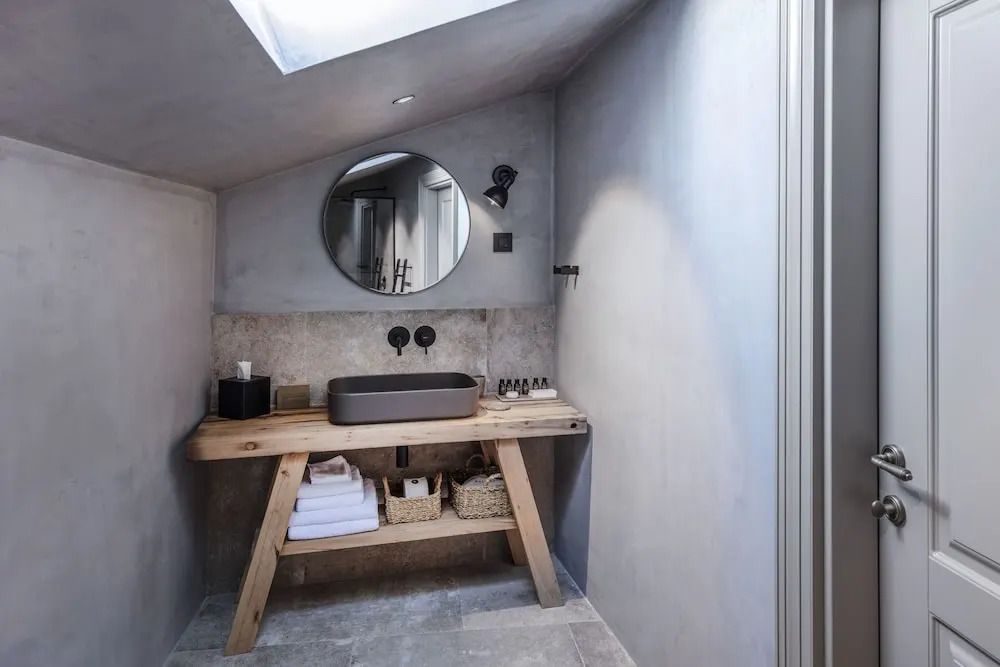 Modernes Badezimmer mit Holzwaschtisch und rundem Spiegel unter Dachfenster.