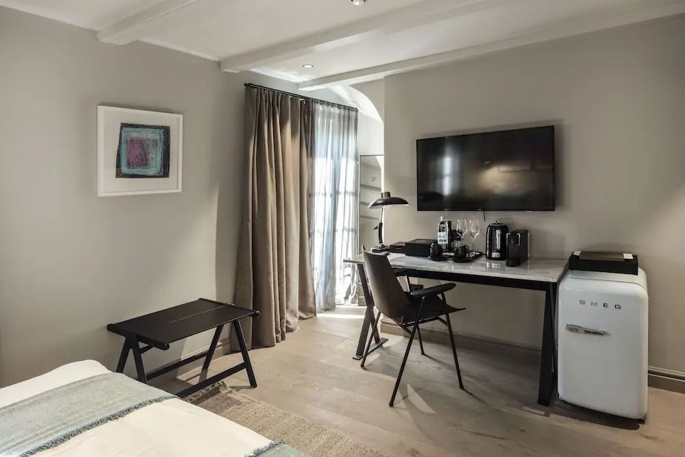 Arbeitsbereich im Zimmer mit Schreibtisch, Stuhl, Fernseher und Kaffeestation.