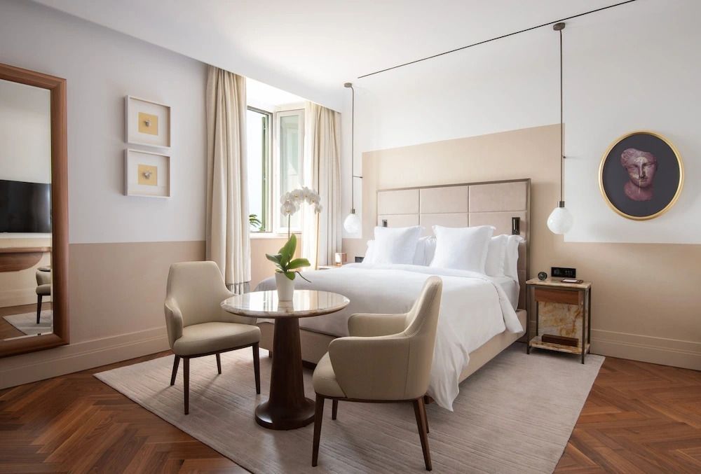 Helles Deluxe Doppelzimmer mit großem Bett, Sitzbereich und Kunstwerken an der Wand