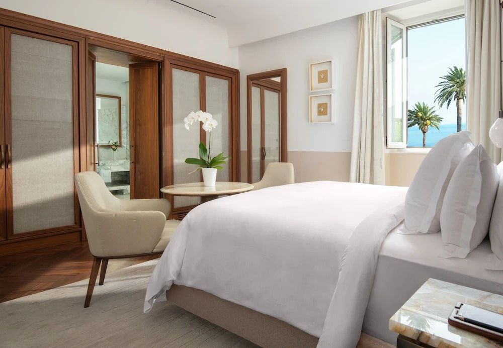 Ein Deluxe Zimmer mit einem großen Bett, Tisch mit Stühlen und Blick auf das Fenster