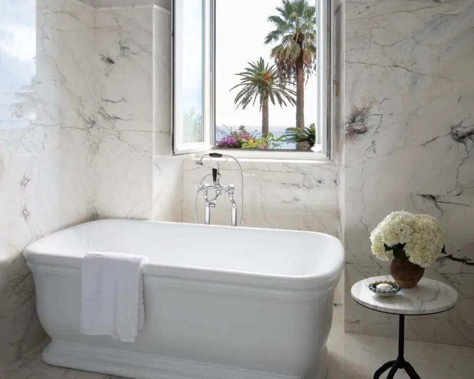 Freistehende Badewanne mit Meerblick und Palmen im Hintergrund im Badezimmer