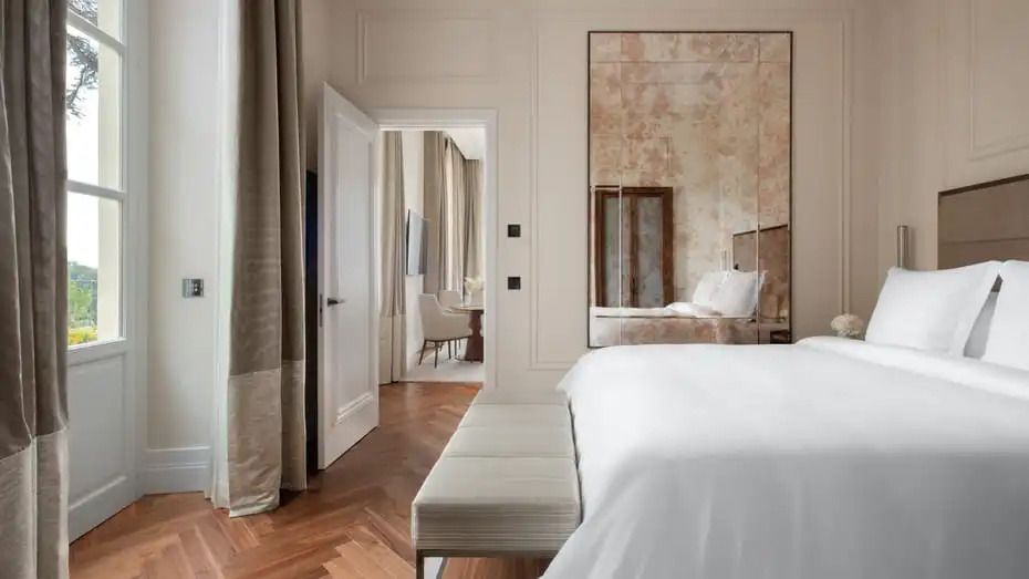 Elegantes Schlafzimmer mit großem Spiegel und Blick in den Wohnbereich der Suite