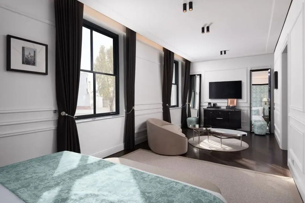 Helles Hotelzimmer mit TV, Sofa und großen Fenstern