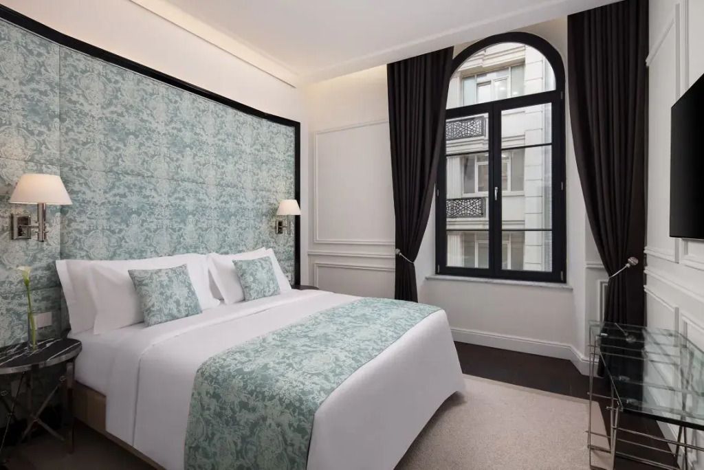 Helles Schlafzimmer mit elegantem Doppelbett und großen Fenstern mit Vorhängen