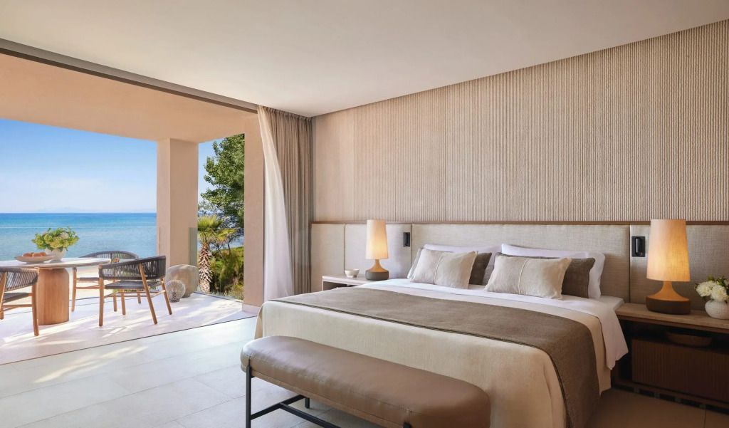 Helles Schlafzimmer mit Doppelbett, offenem Balkon und Meerblick