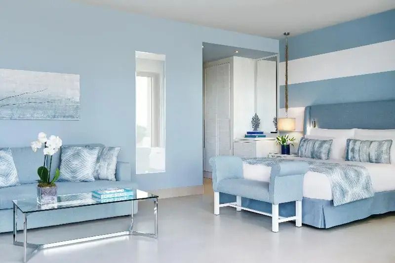 Modernes Doppelzimmer in Blautönen mit Sitzbereich und Meerblick