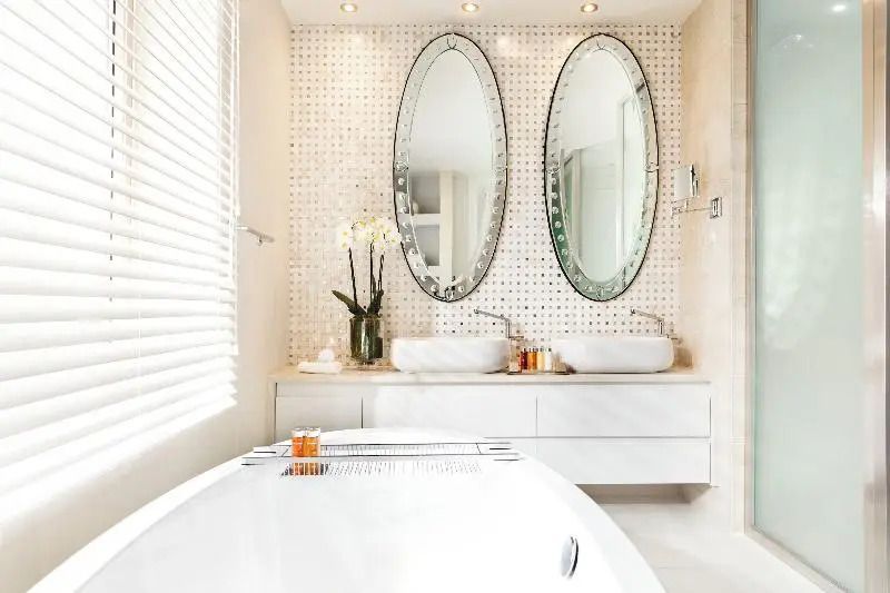Luxuriöses Badezimmer mit freistehender Badewanne und zwei ovalen Spiegeln