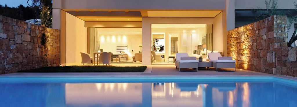 Luxuriöse Suite mit offenem Blick auf den beleuchteten Pool bei Nacht