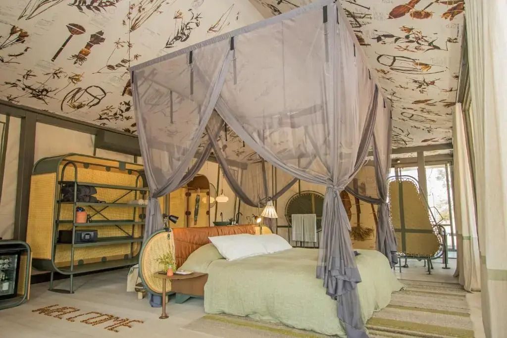 Geräumiges Schlafzimmer mit elegantem Baldachinbett und dezentem Design im Saseka Tented Camp.