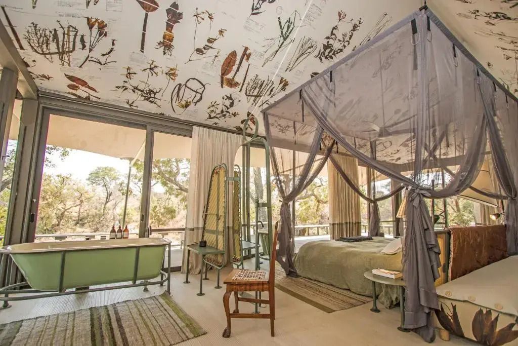 Helles Schlafzimmer mit Baldachinbett und dekorativer Deckenkunst im Saseka Tented Camp.