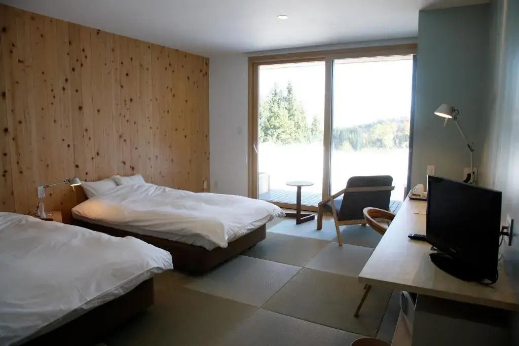 Modernes Hotelzimmer mit zwei Einzelbetten, Holzwänden und Blick ins Freie.