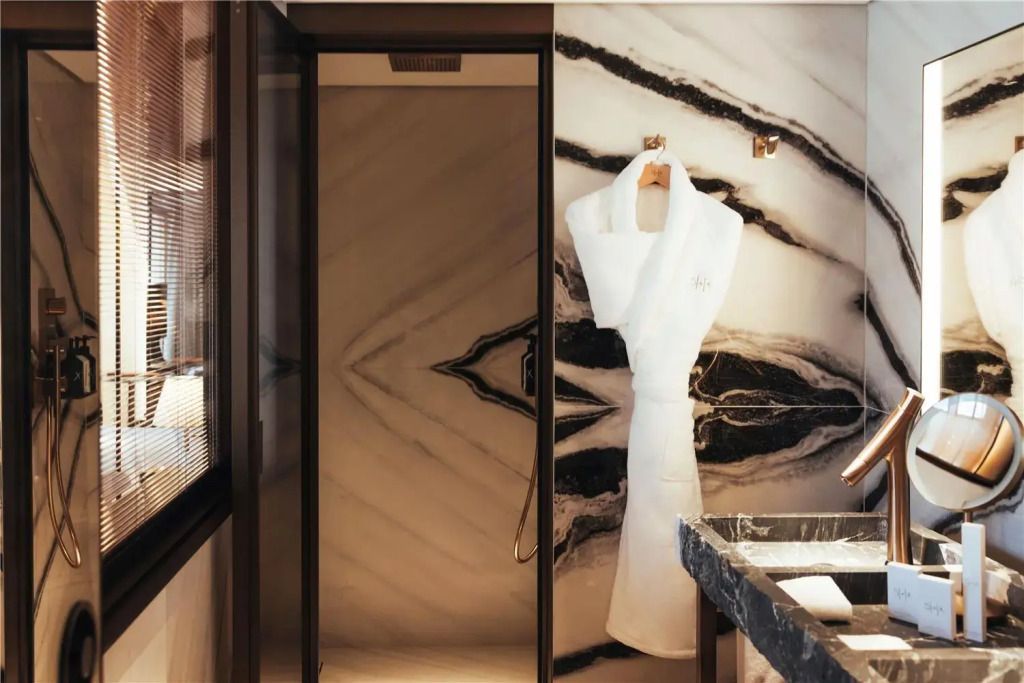 Luxuriöses Badezimmer mit Marmordesign und weißen Bademänteln