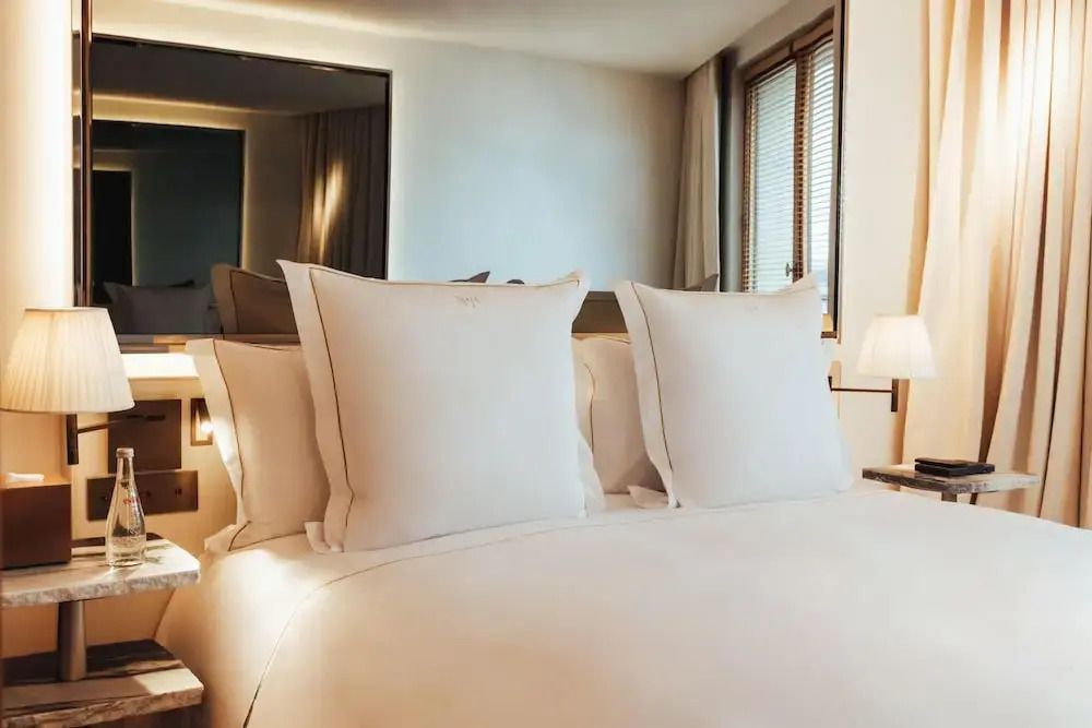 Komfortables Bett mit mehreren Kissen und natürlichem Lichteinfall