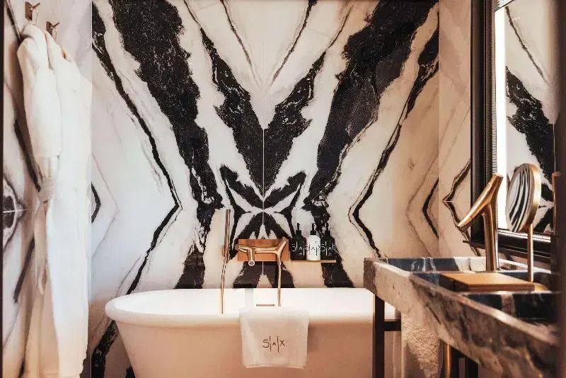 Luxuriöse Badewanne in modernem Badezimmer mit kunstvoller Marmorrückwand.