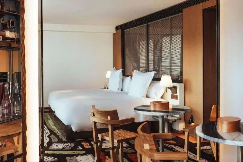Geräumiges Hotelzimmer mit zwei großzügigen Betten und Holzmöbeln.