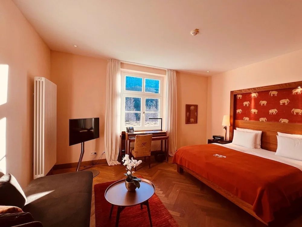 Sonnenbeschienener Raum mit Bett und Schreibtisch in der Deluxe Doppel Junior-Suite.