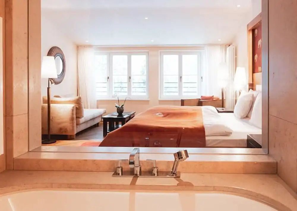 Blick über die Badewanne in stilvolle Suite mit Sitzbereich.